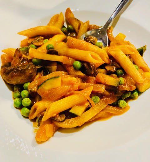A plate of pasta and vegetables with a spoon in it
