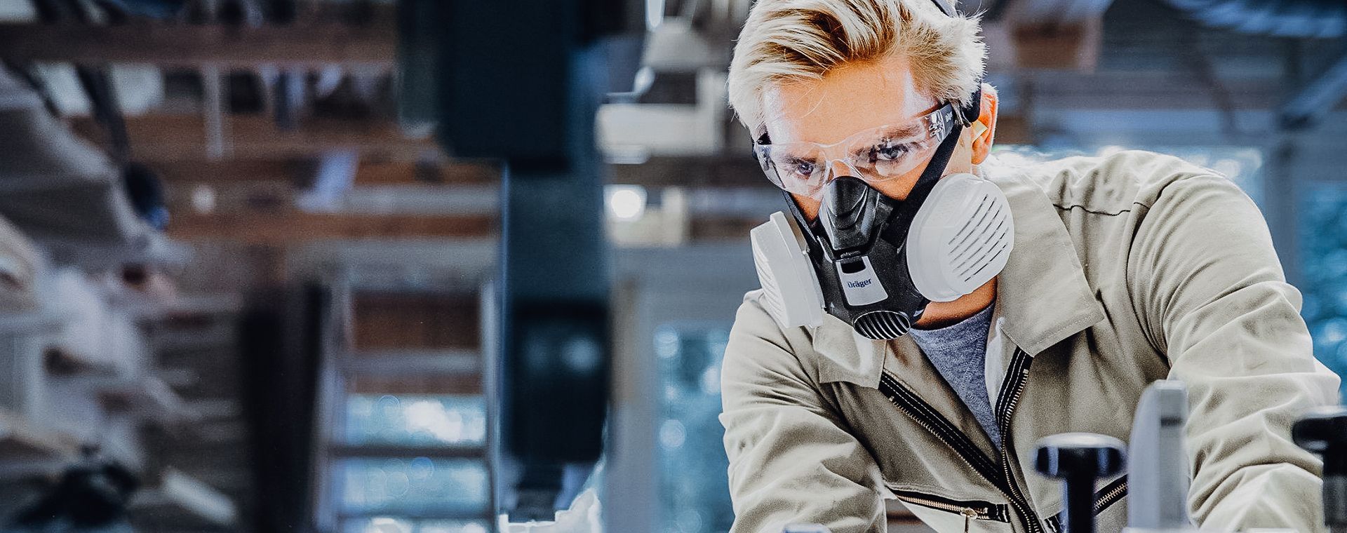 A woman wearing a gas mask and goggles is working in a factory.