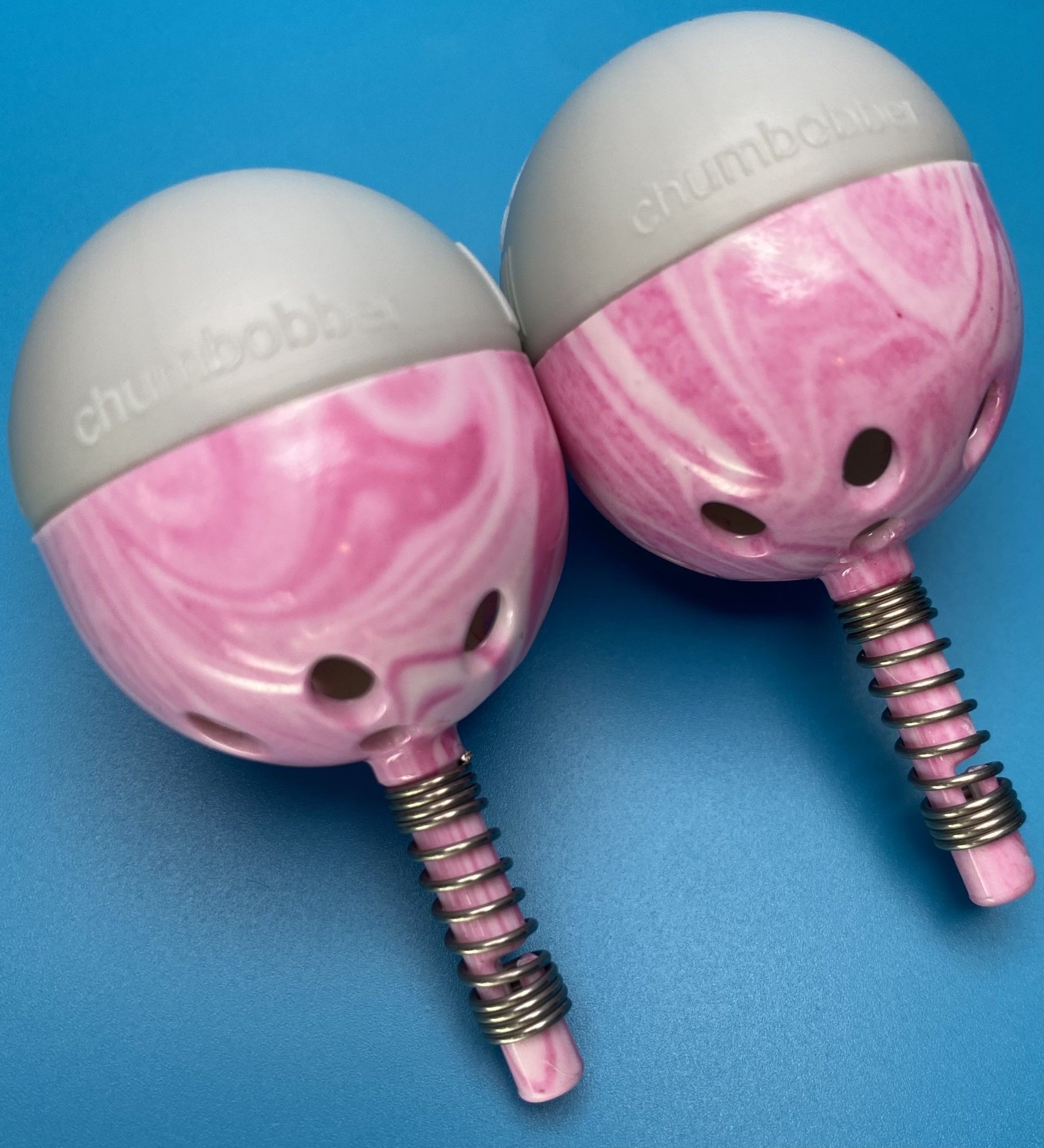 A pair of pink and gray dumbbells on a blue surface