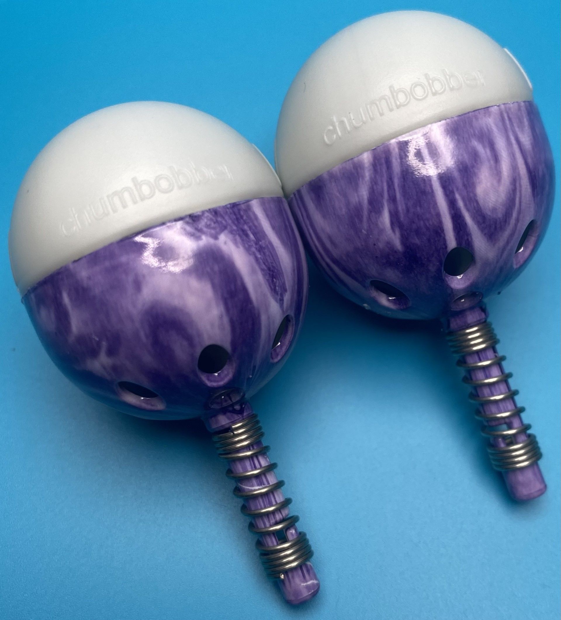 A pair of purple and white thumbbobs on a blue surface