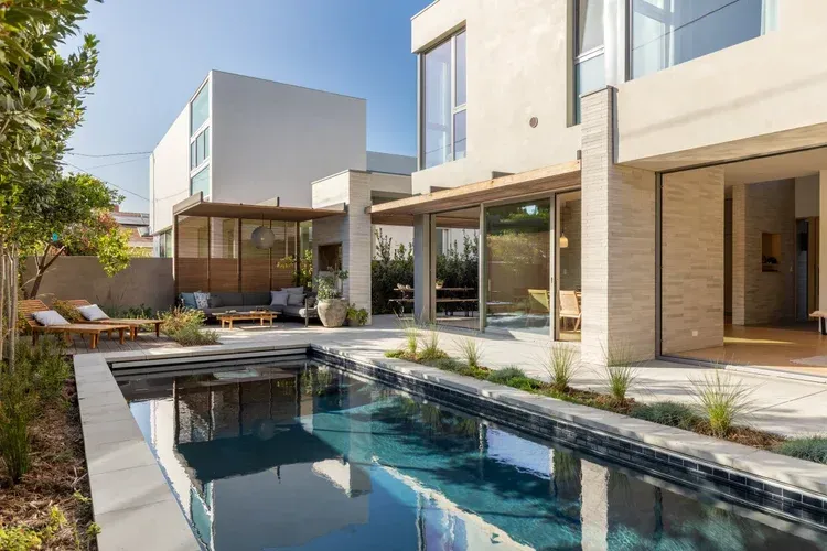 Modern house courtyard with a narrow swimming pool, glass doors, and patio seating