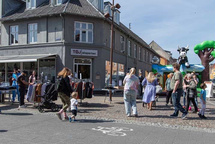 Udendørs marked med mennesker; oppustelig ko på struktur.
