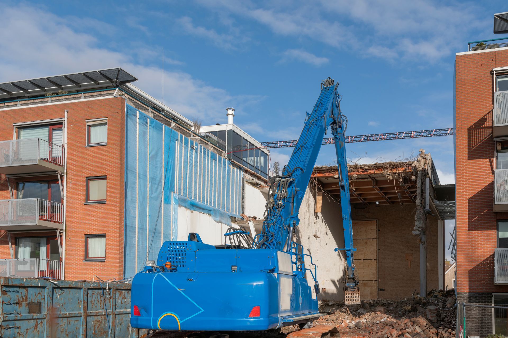 A blue Hitachi ZX170W-3 wheeled excavator stands outside on a demolition site.