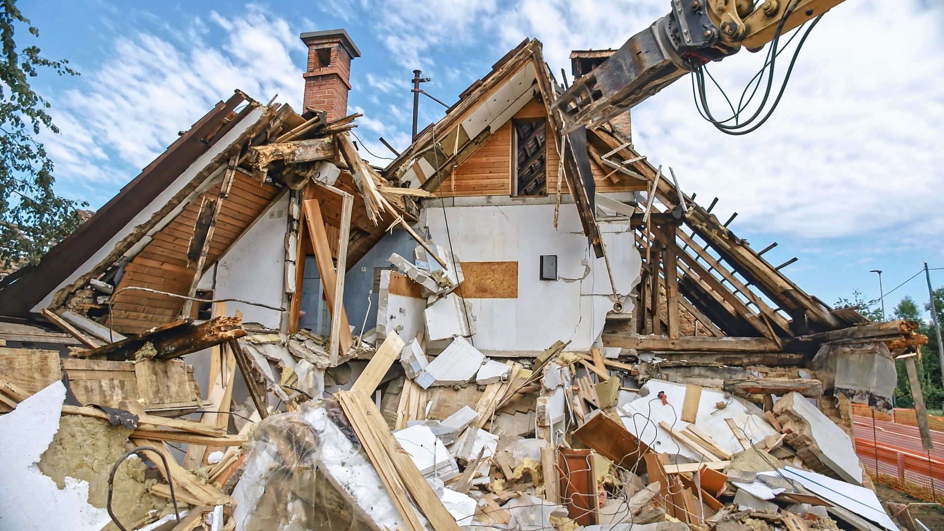 Excavator demolishes house with debris and rubble scattered around. Excavator demolishes house with debris and rubble scattered around.