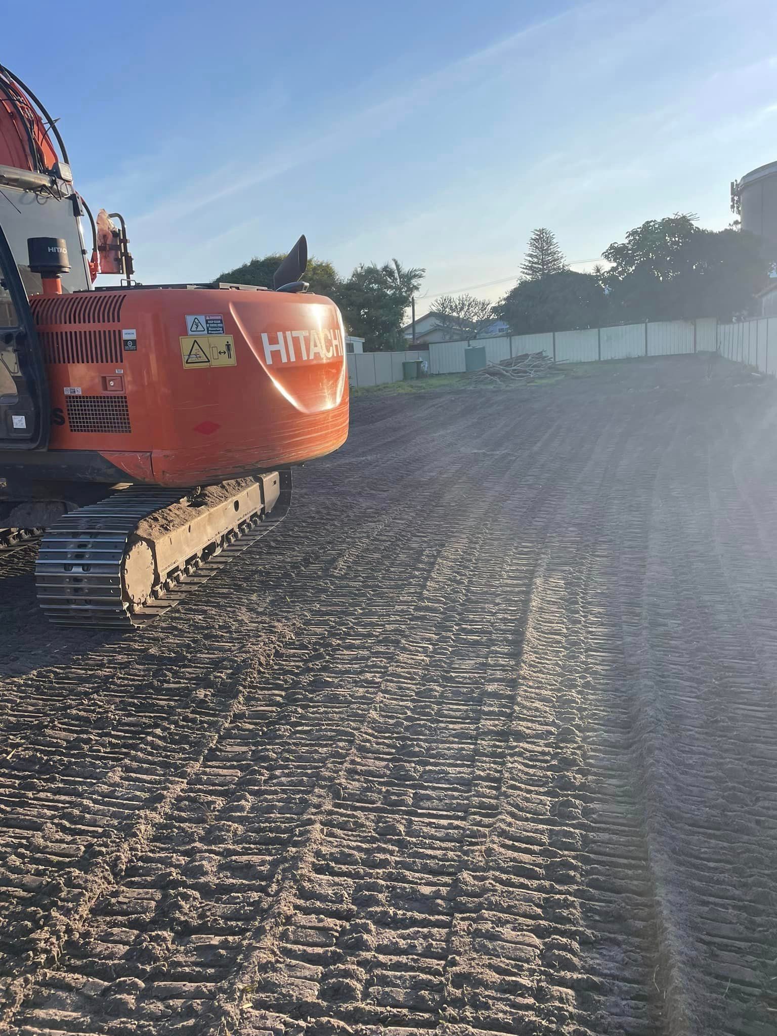 A large orange excavator is sitting on top of a dirt field.