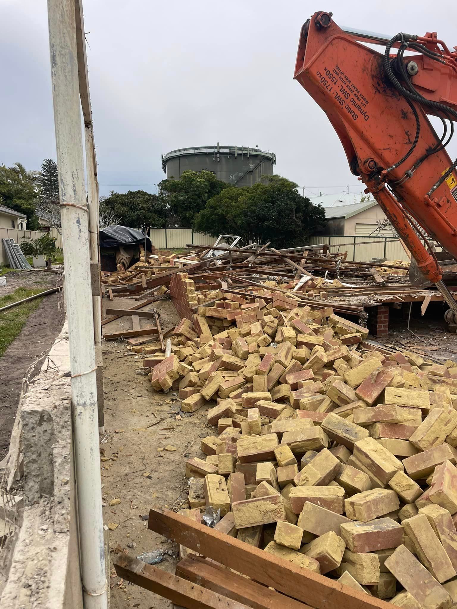A pile of bricks is being demolished by an excavator.