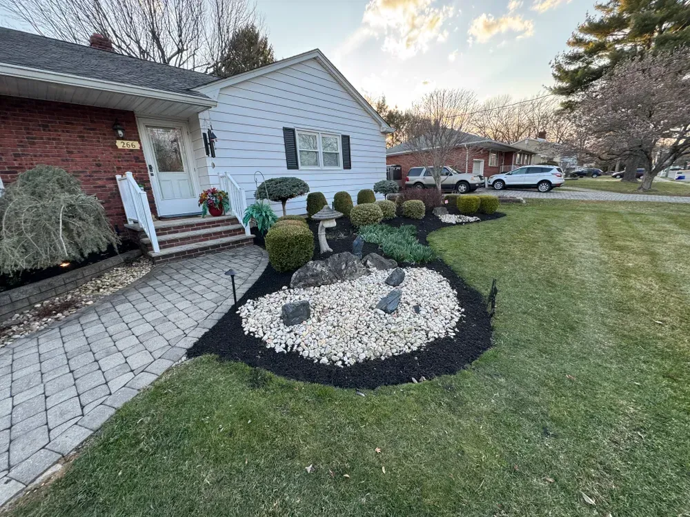 A white house with a brick walkway and a lush green lawn in front of it.