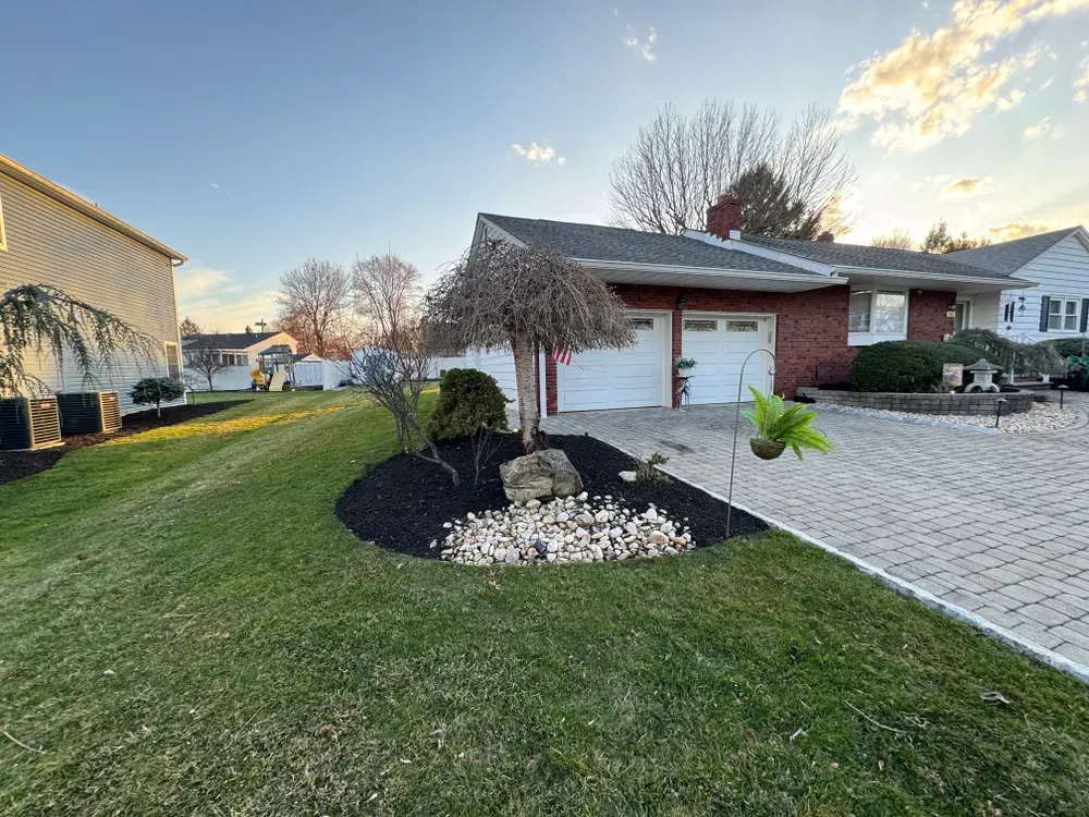 A house with a large lawn and a driveway in front of it.
