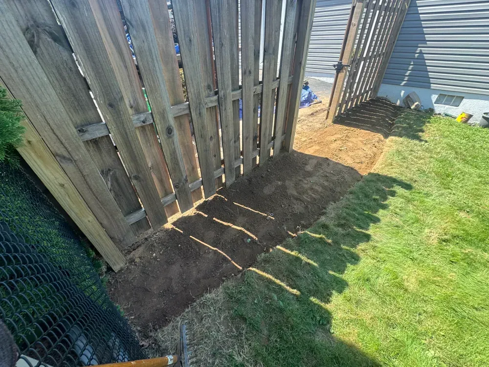 A wooden fence is being built in a backyard.