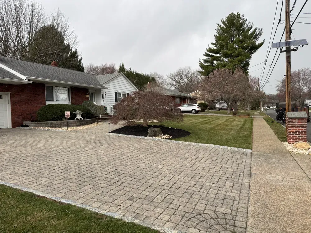 A brick driveway leading to a house in a residential neighborhood.