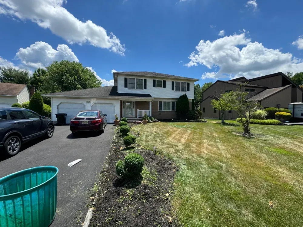 A car is parked in front of a house on a sunny day.