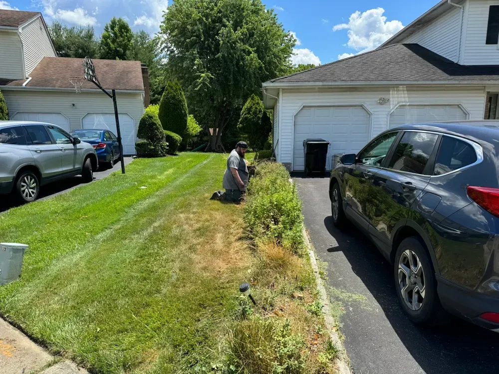 A man is kneeling down next to a car in front of a house.