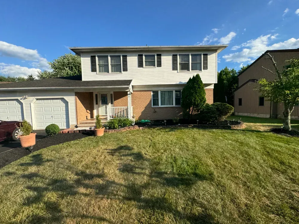 A large house with a lush green lawn and a car parked in front of it.