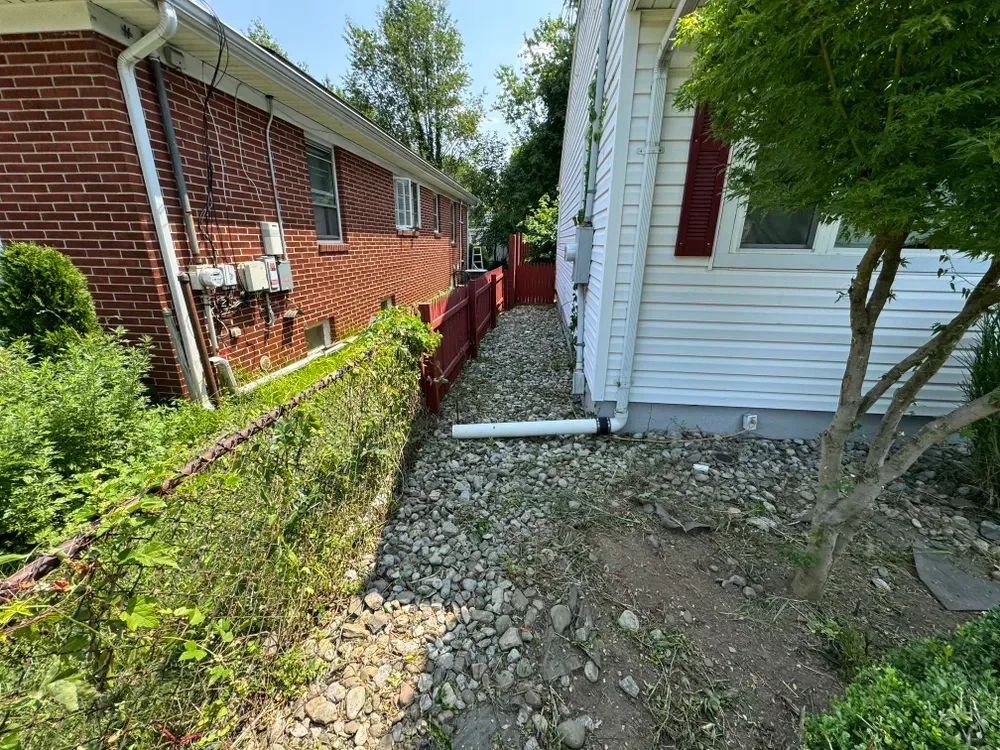 A dirt path leading to a brick house with a red fence.