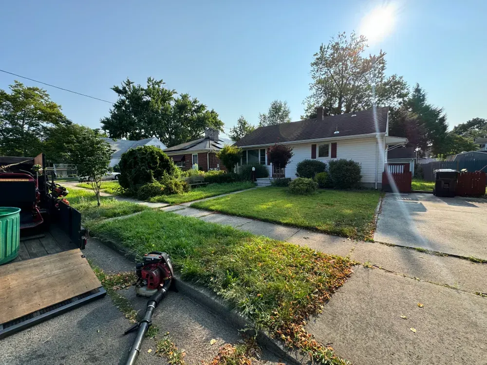 A lawn mower is sitting on the sidewalk in front of a house.