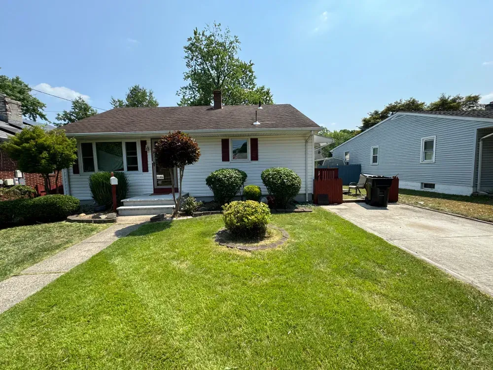 A white house with a large lawn in front of it.
