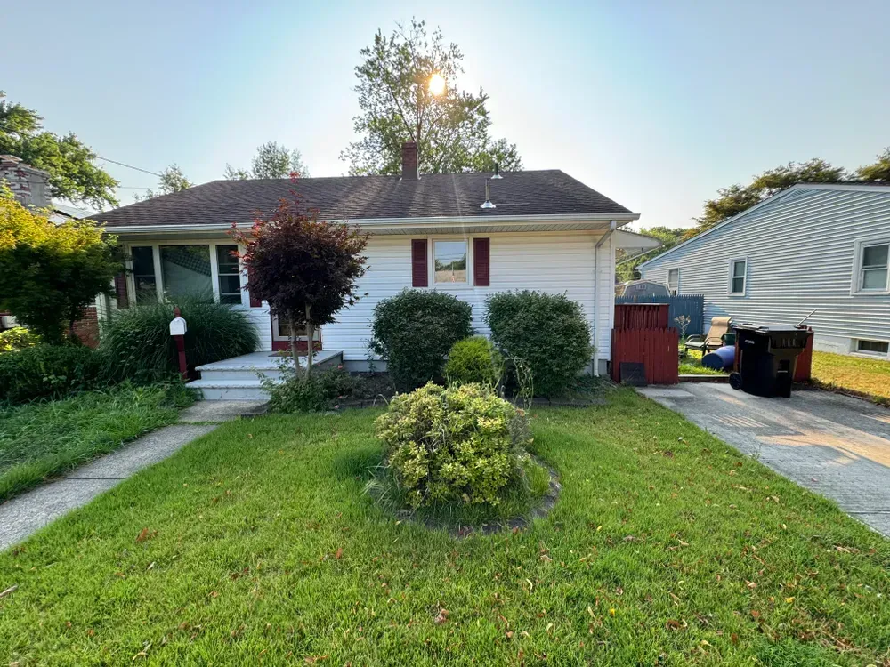 A white house with a large lawn in front of it.