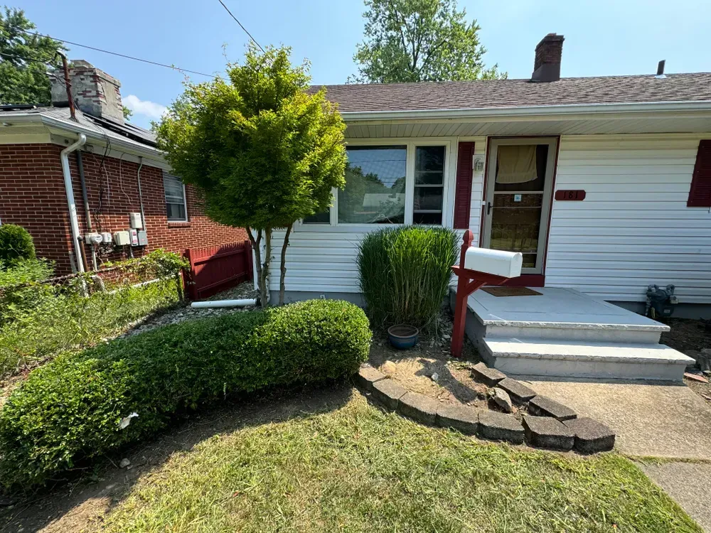 A white house with a red door and a mailbox in front of it.