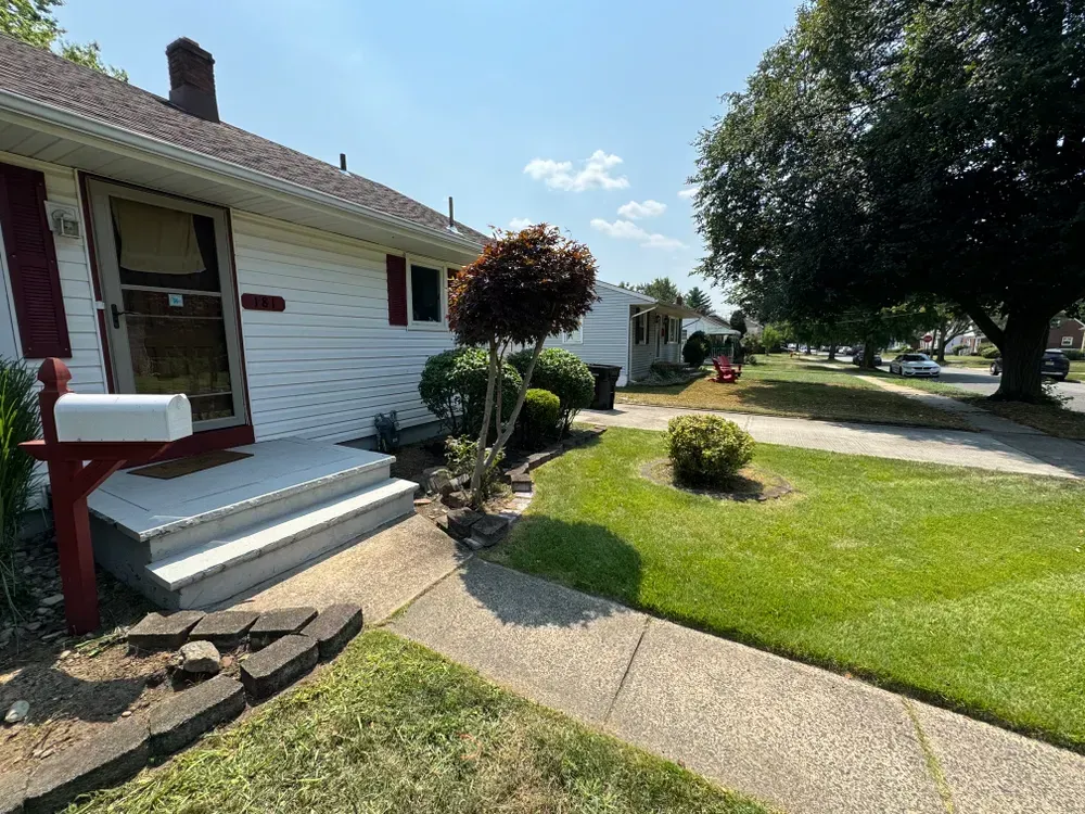 A white house with red shutters and a mailbox in front of it.