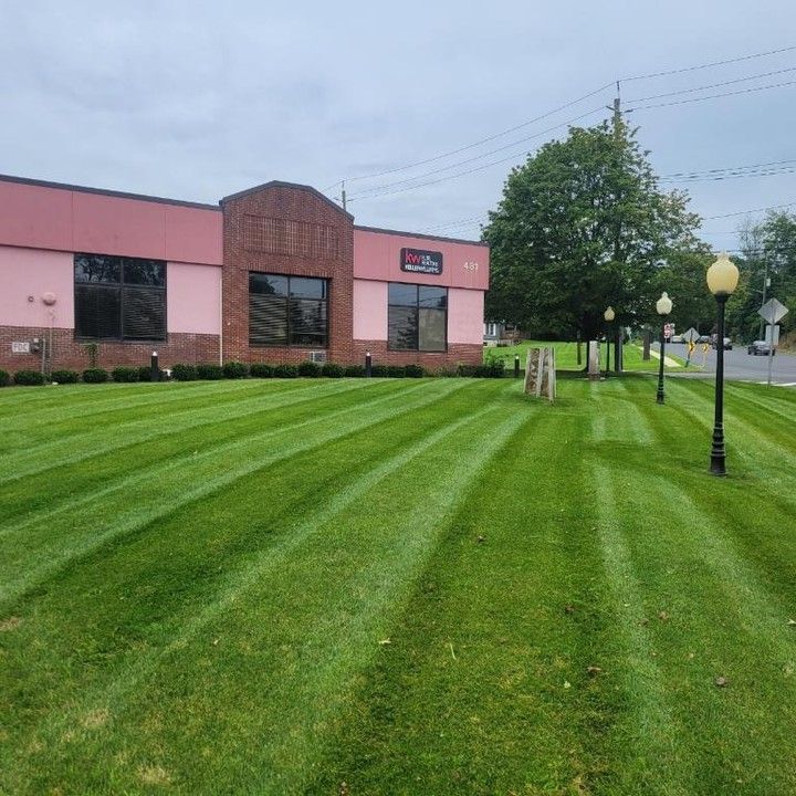 A large pink building with a lush green lawn in front of it.