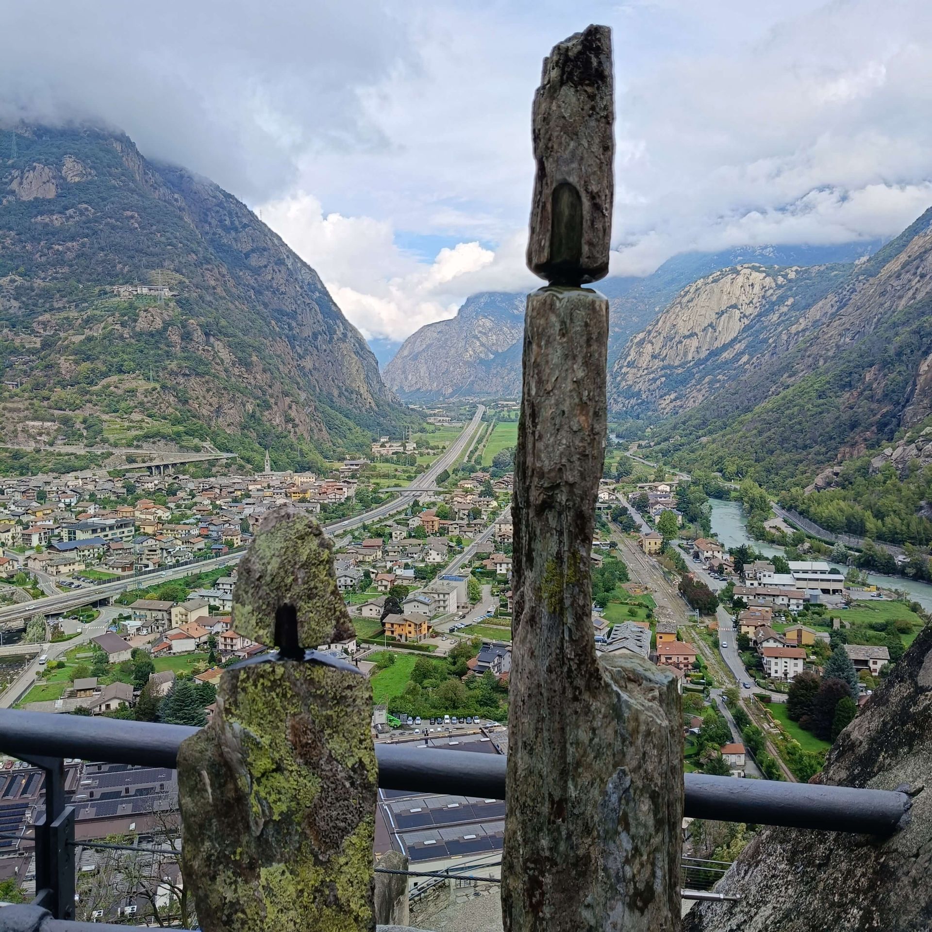 Opera di Donato Savin con stele in pietra, esposta al Forte di Bard con panorama alpino sullo sfondo.