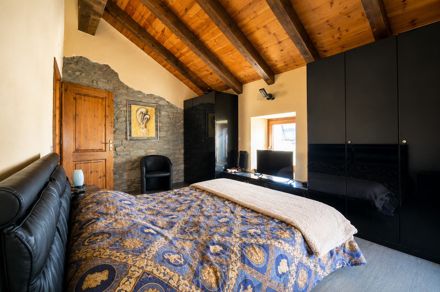Camera matrimoniale di The Old Barn by Roby con soffitto in legno a vista, pareti in pietra naturale e arredi in stile alpino.