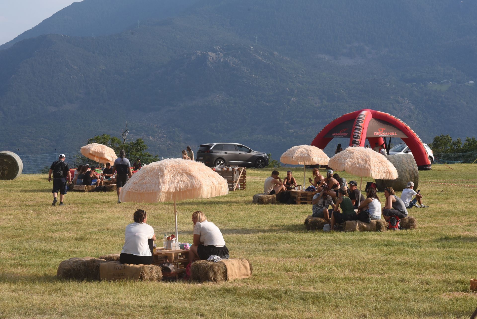 Spettatori rilassati seduti su balle di paglia nel prato, immersi nell’atmosfera del Pekelin Strong Music Fest