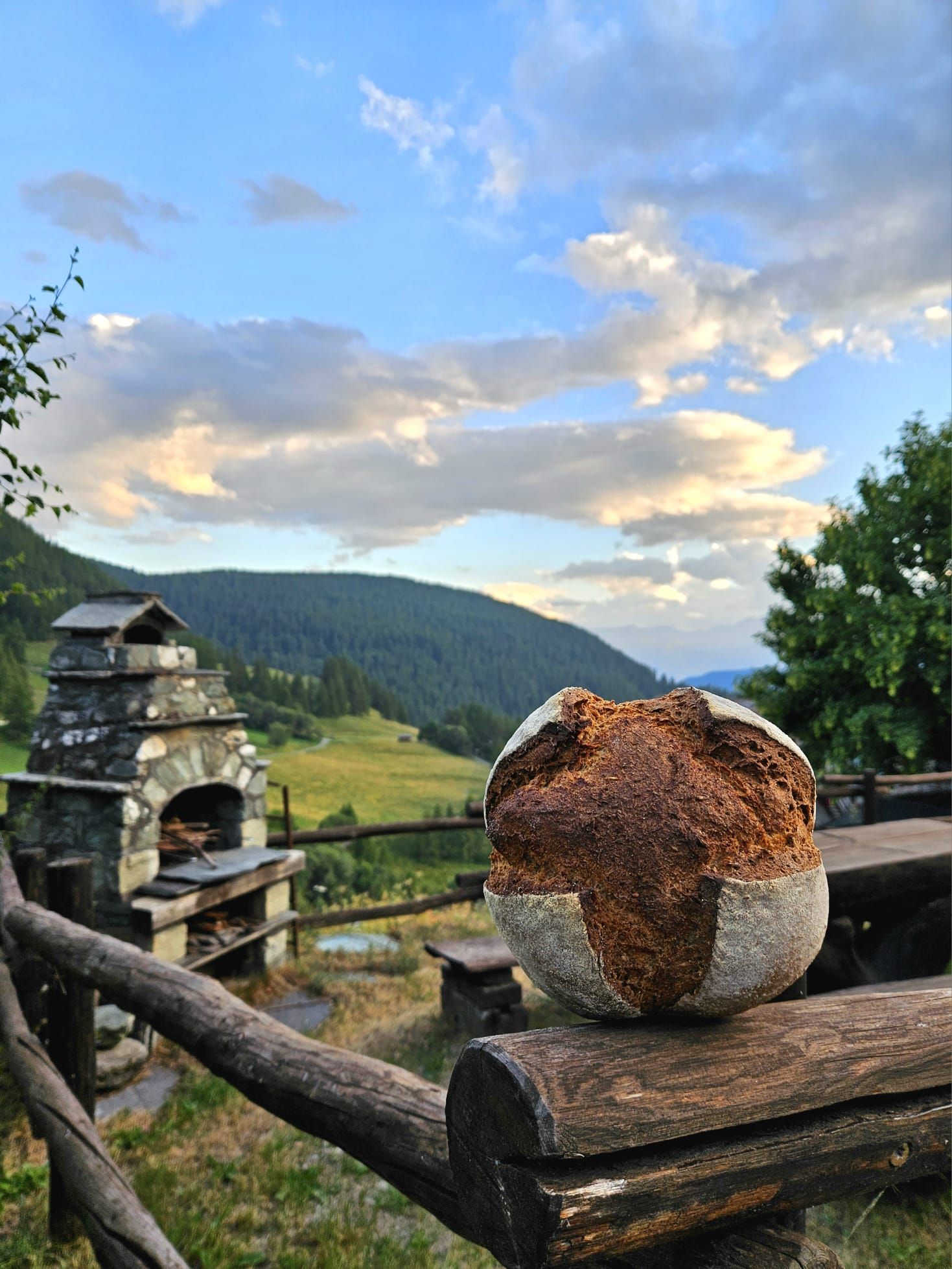 pane artigianale del forno di Liussel in primo piano con paesaggio di Chamois Valle d’Aosta sullo sfondo