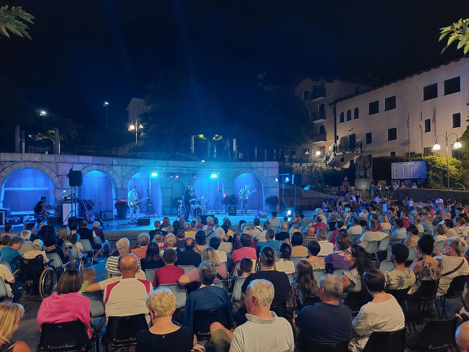 Spettatori seduti ad ascoltare il concerto in piazza a Saint-Vincent, immersi nell’atmosfera estiva del borgo alpino