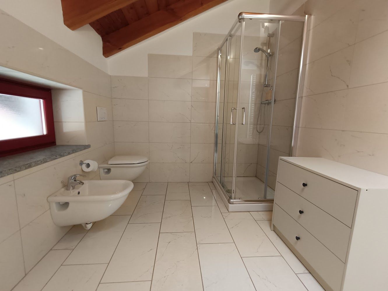 Salle de bain lumineuse avec commode et douche