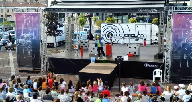 Maga Gaia in abiti colorati mentre stupisce i bambini con uno spettacolo di magia
