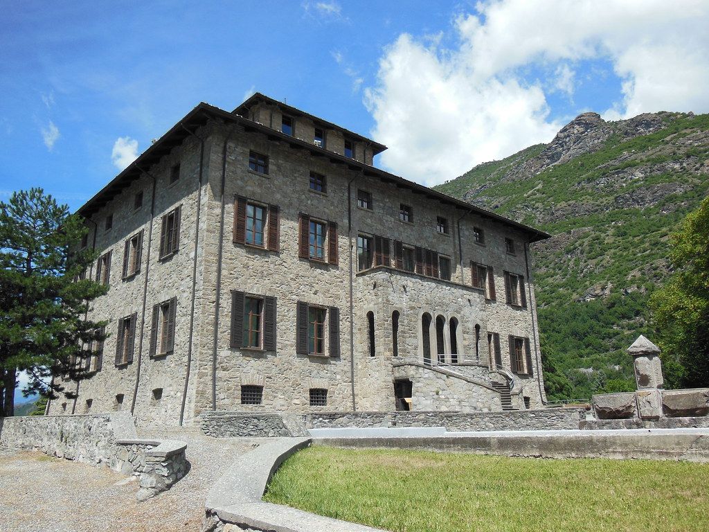 Exterior view of Castello Gamba surrounded by trees and mountains