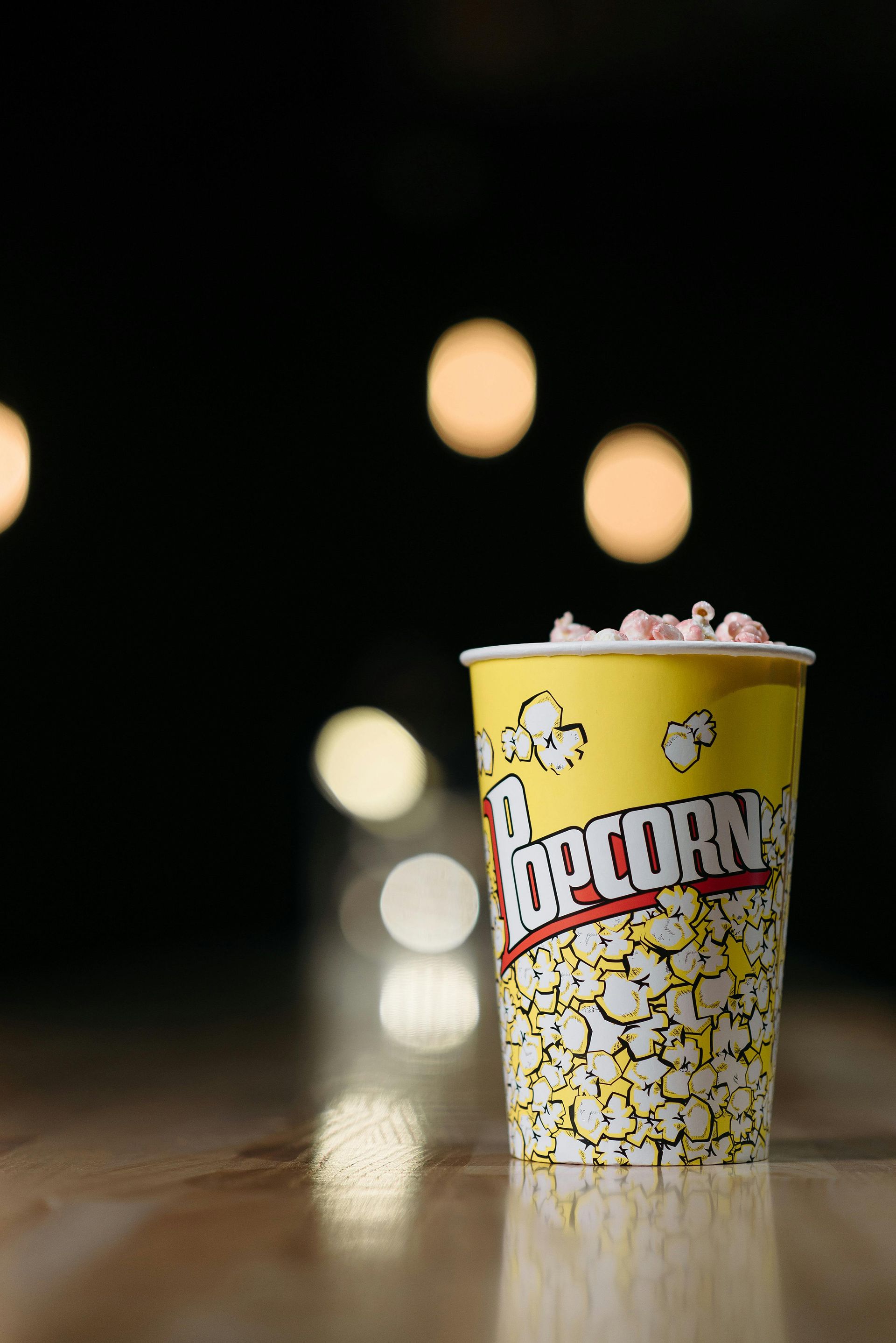 Pop corn in primo piano con sfondo sfocato di una proiezione all’aperto, simbolo del cinema estivo sotto le stelle a Saint-Vincent

