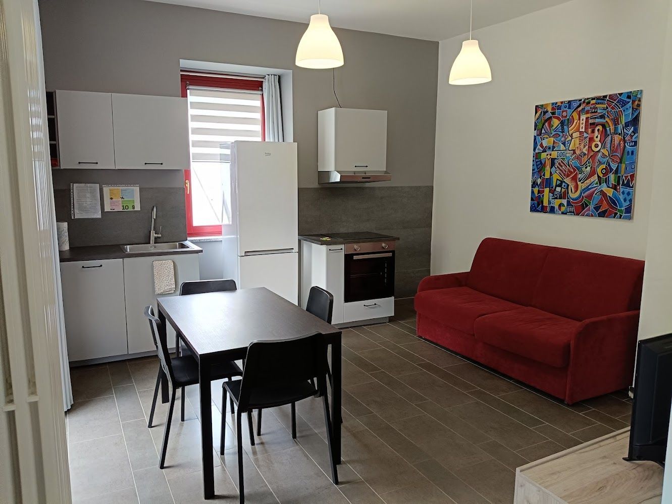 Salon lumineux avec canapé convertible et coin cuisine équipé