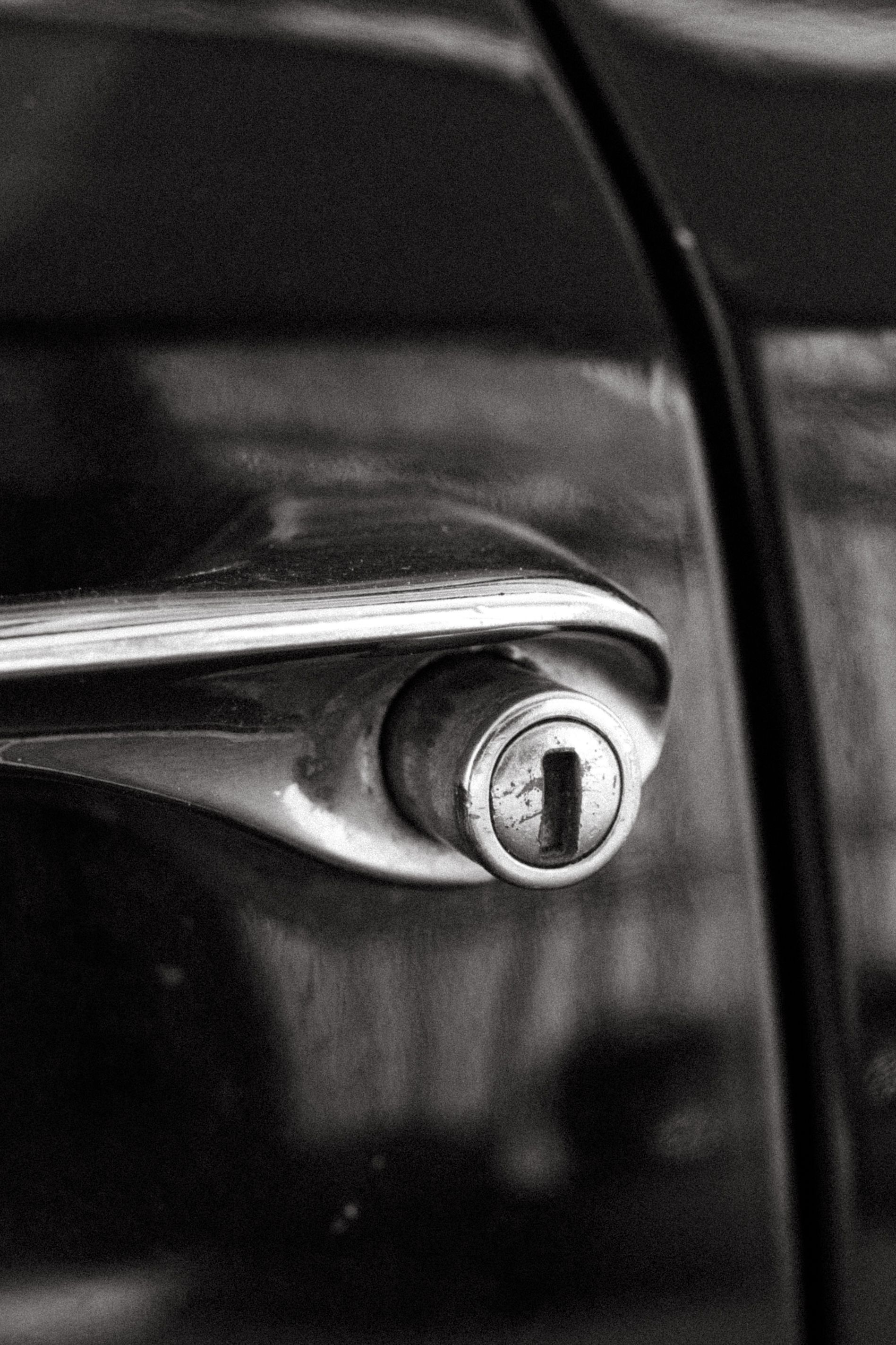 Close-up of a car door handle with a keyhole, in black and silver.