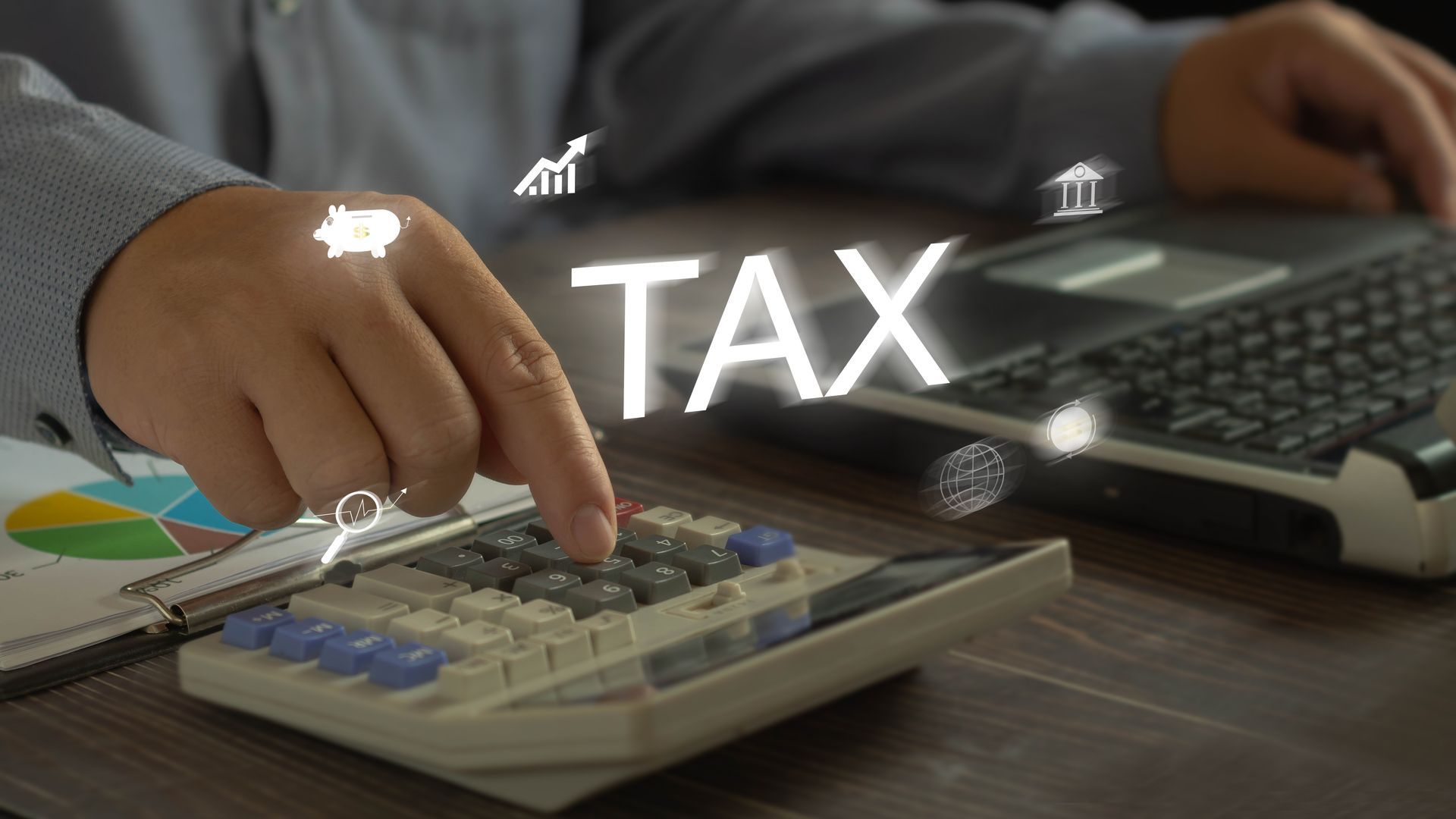 Person calculating taxes with a calculator beside a laptop, with “TAX” text overlay