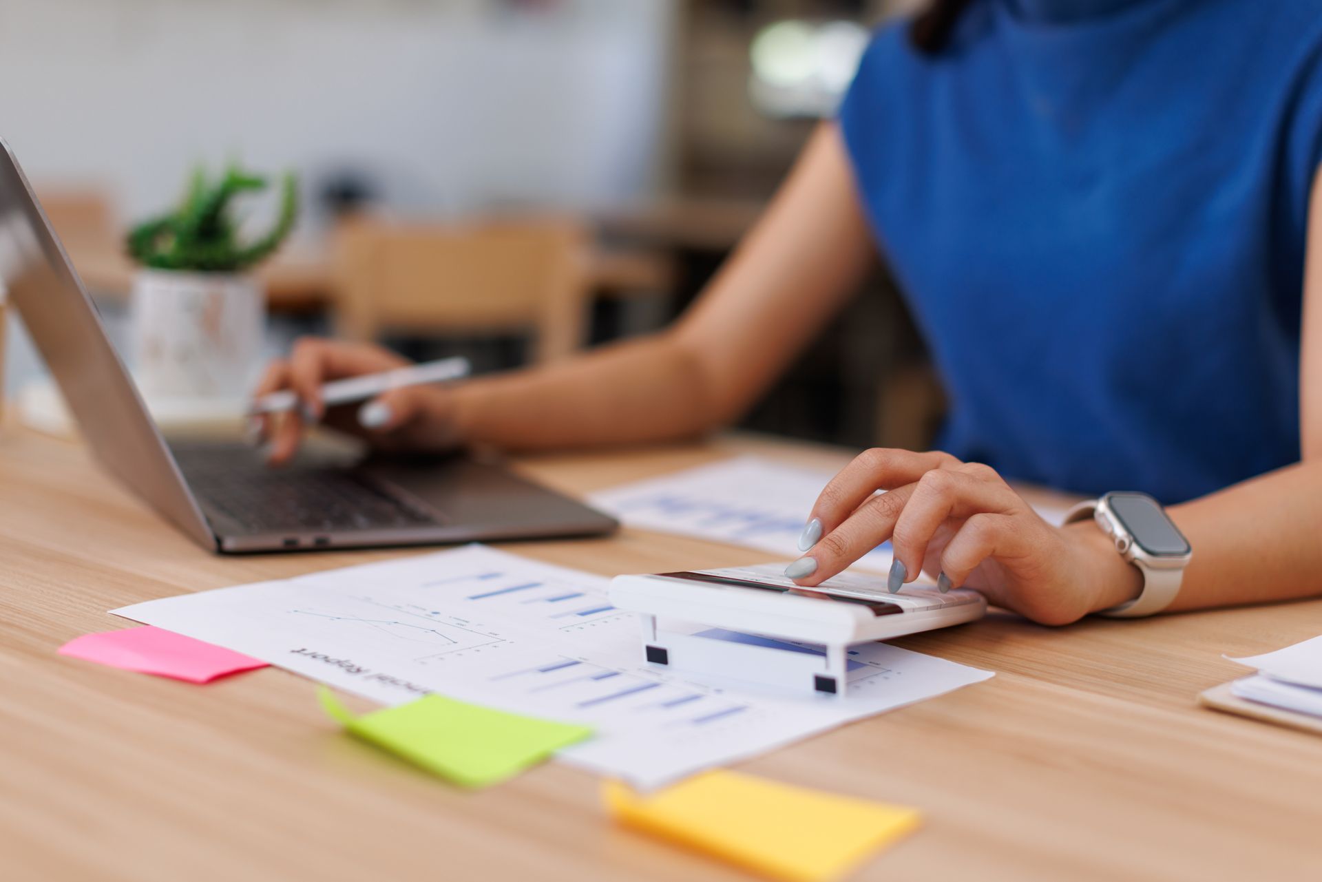 Person working at a desk with a laptop, notebook, and colorful sticky notes
