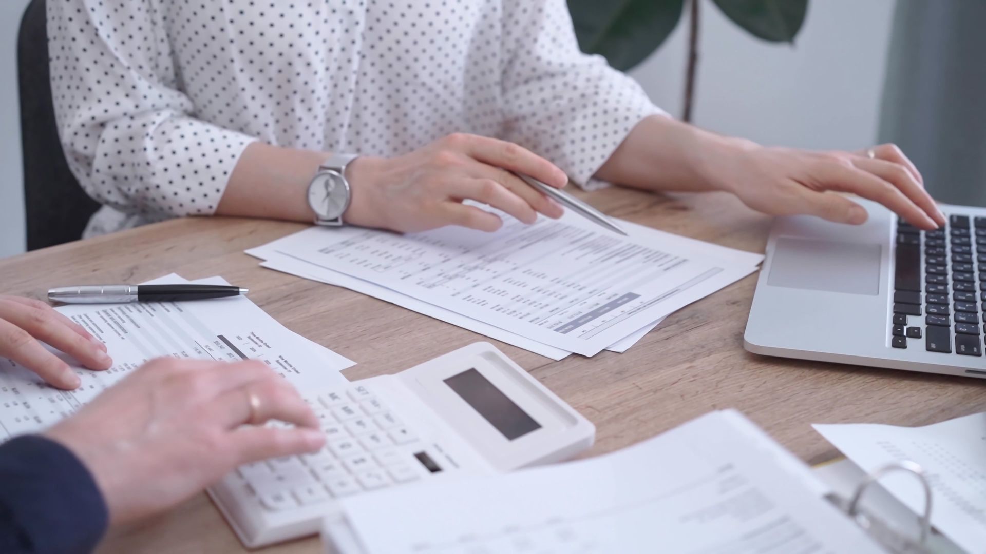 People reviewing printed documents and a laptop at a desk during a meeting