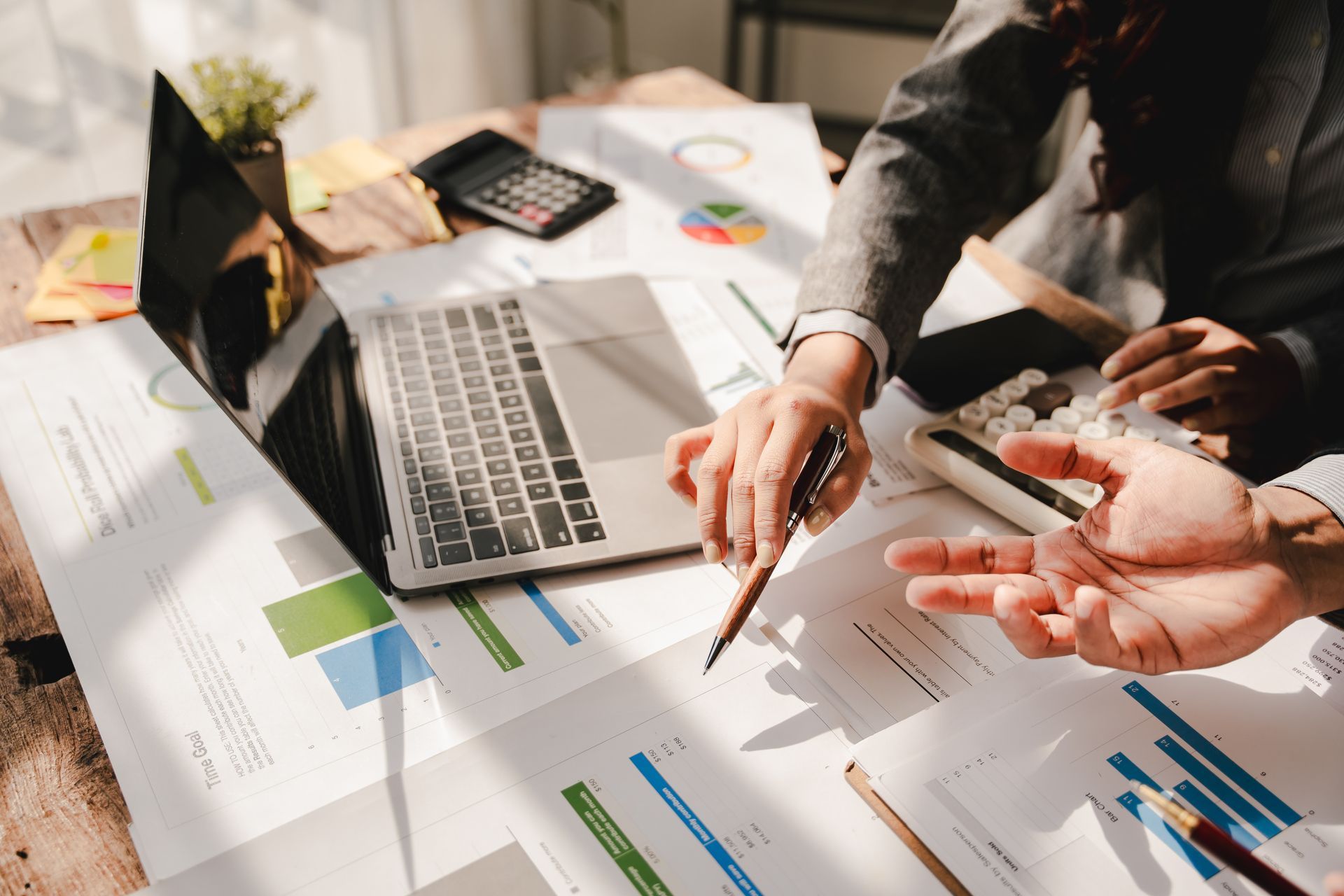 Team reviewing charts and a laptop during a business meeting on a bright desk