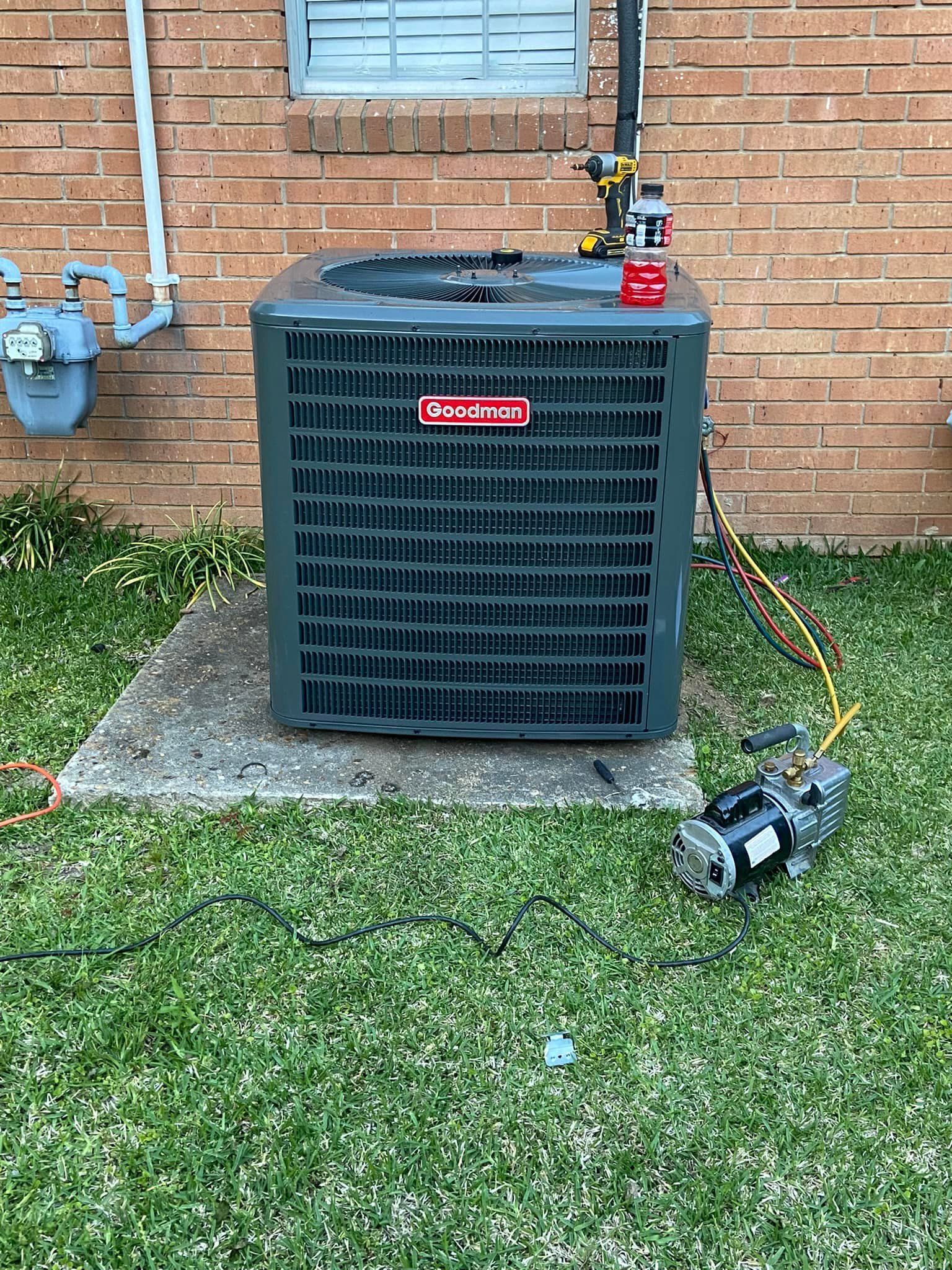 Outdoor air conditioning unit next to a brick wall and gas meter. A vacuum pump is connected to the unit.