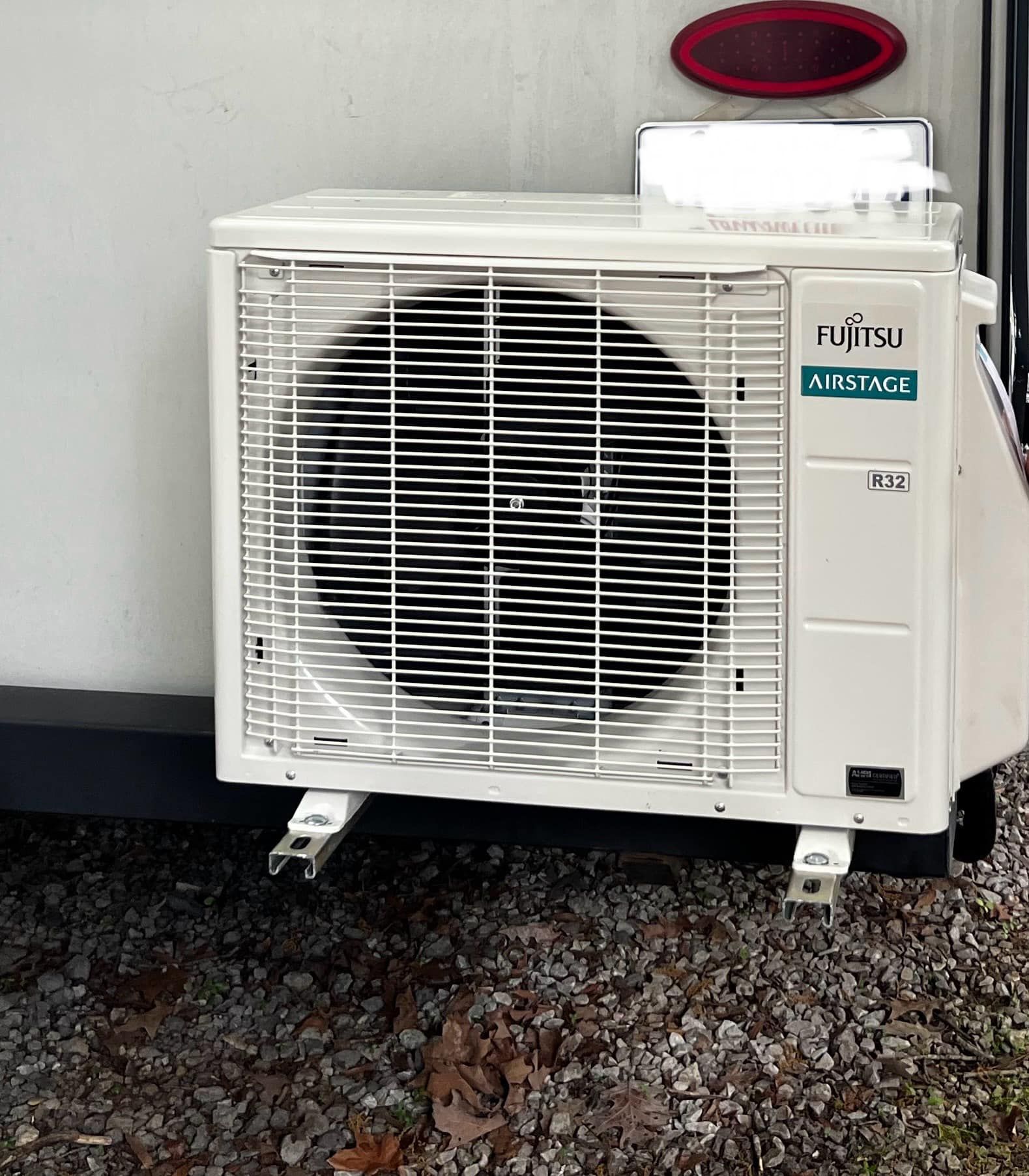 Fujitsu air conditioner unit mounted on exterior RV wall; white, black fan blades visible.