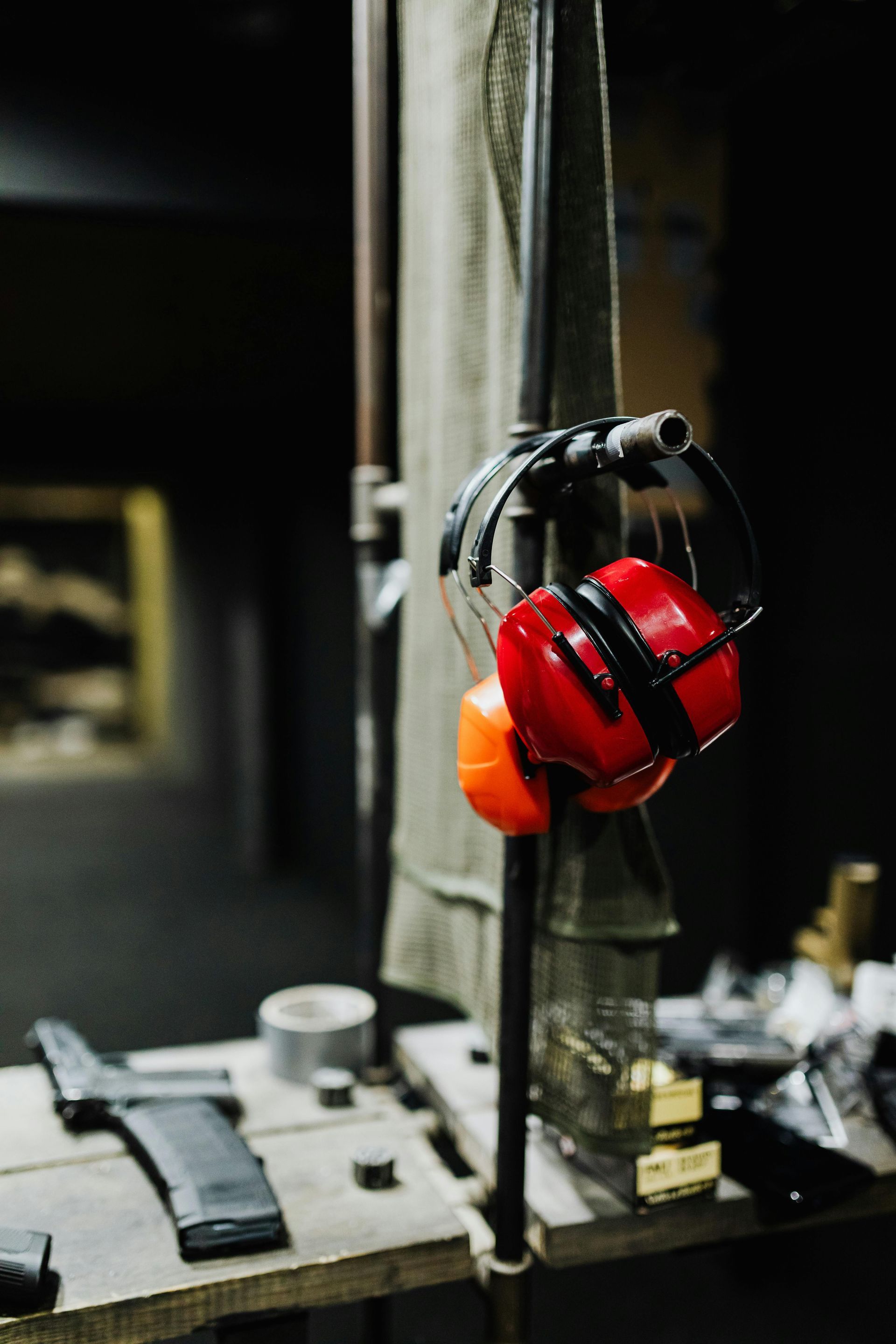A pair of red ear muffs hanging from a metal pole.