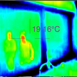 A thermal image of two people through a window