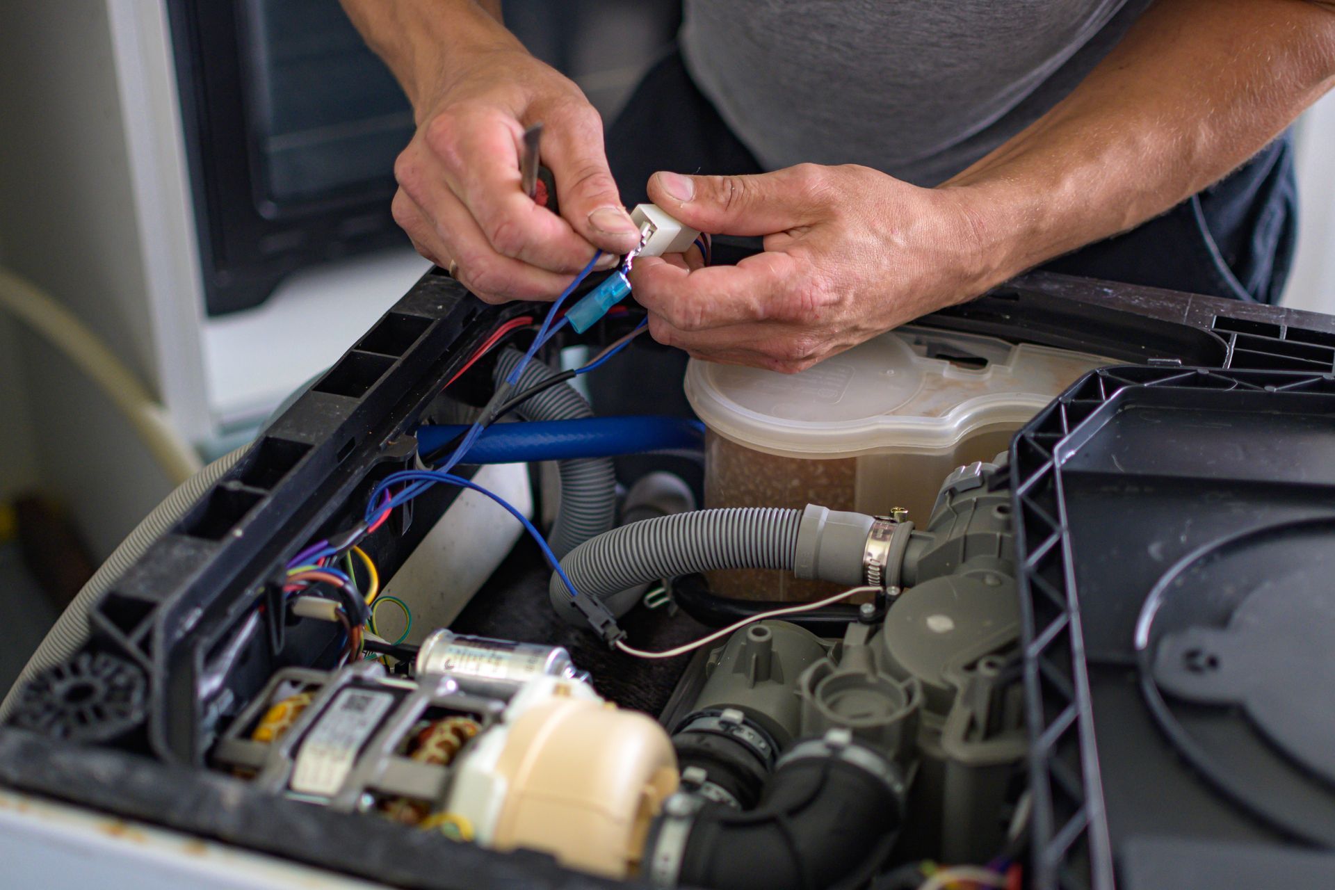 Hands connecting wires inside a machine. Black casing, various components visible.