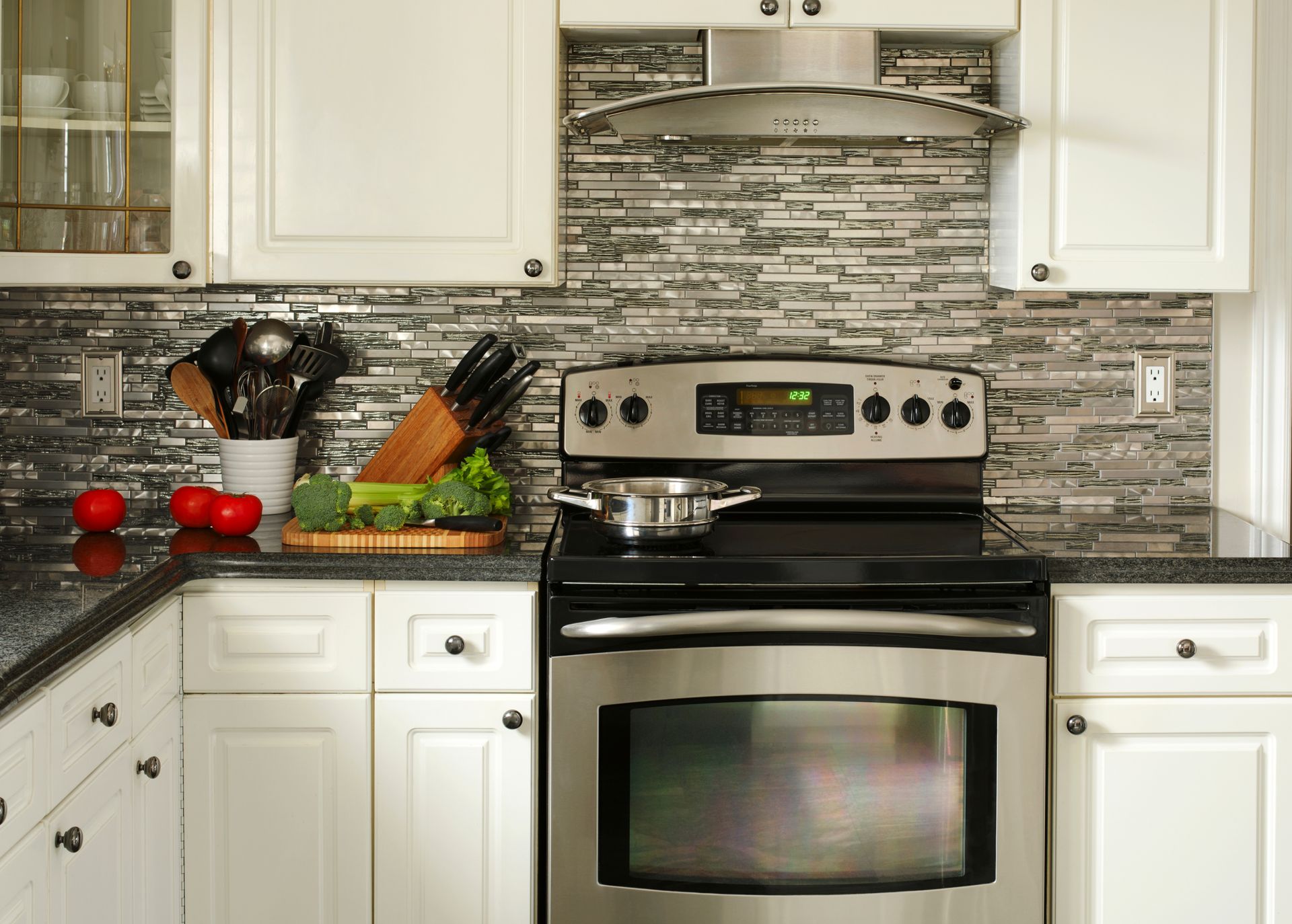 An oven installed in a white cabinet. The oven door is open. Shelf above holds hardware and a utility knife. An oven installed in a white cabinet. The oven door is open. Shelf above holds hardware and a utility knife.