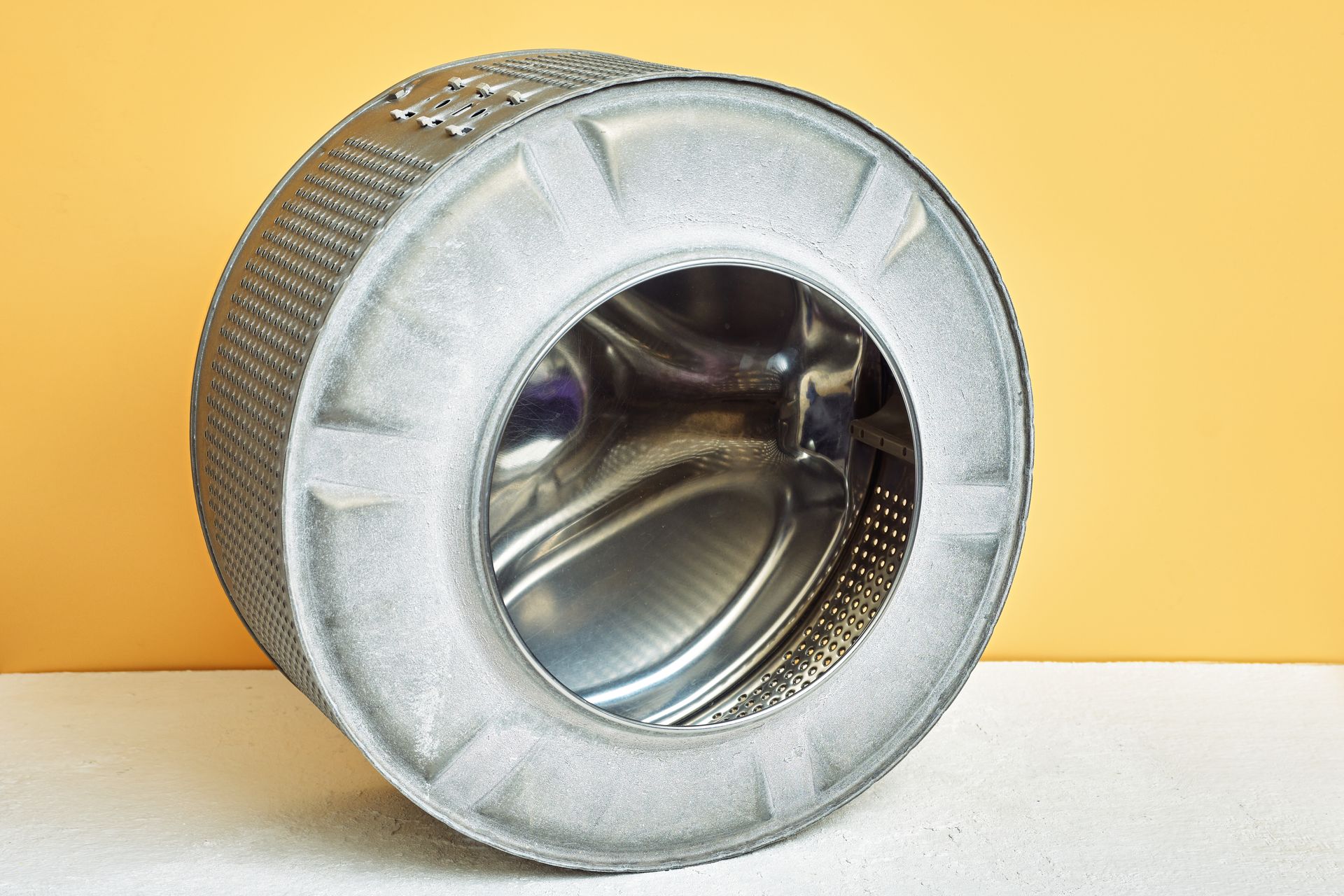 Two white washing machines, one with an open door, against a grey wall.