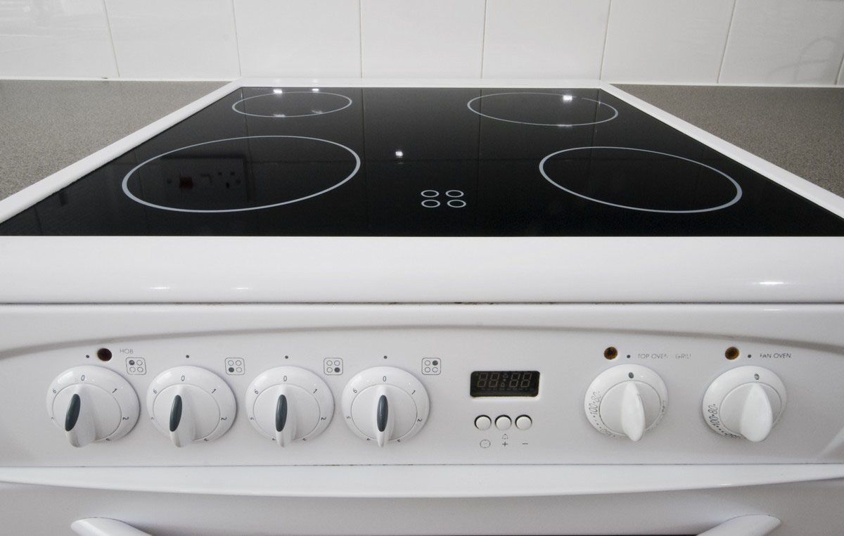 White electric stove with black glass cooktop and control knobs.