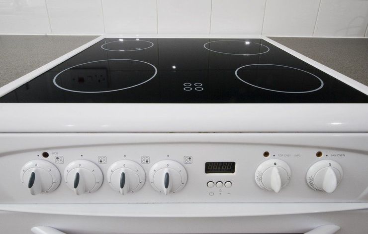 White electric stove with black glass cooktop and control knobs. White electric stove with black glass cooktop and control knobs.
