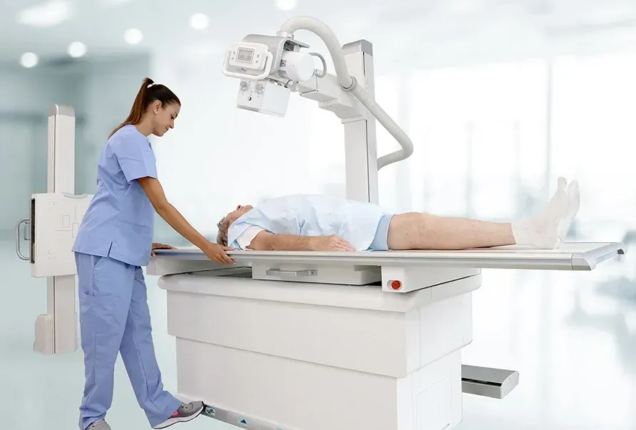A nurse is standing next to an x-ray machine with a patient laying on it.
