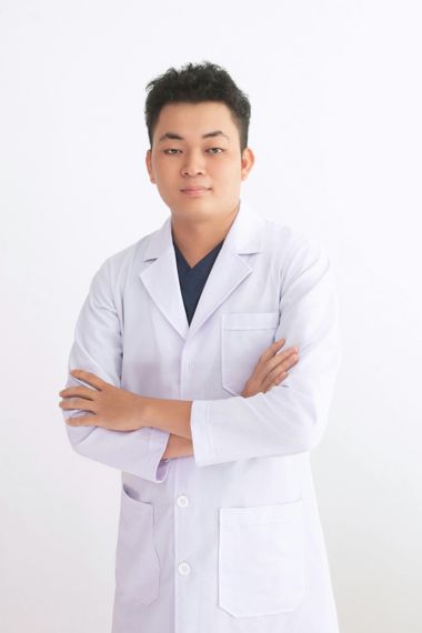 一名身穿白色實驗服的人雙手交叉，站在純白色背景前。